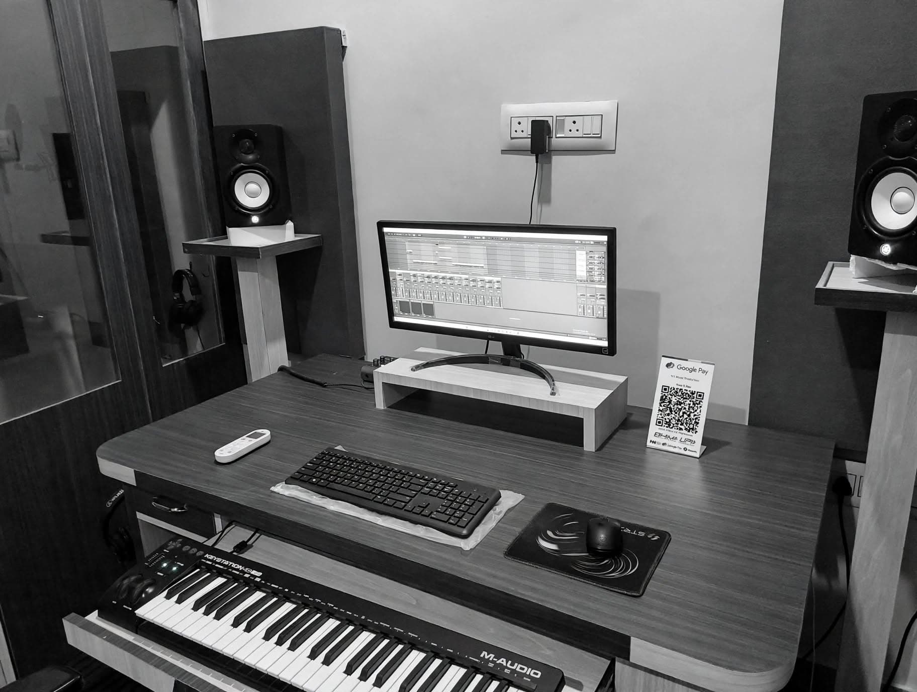 Production desk with monitor, MIDI keyboard, and studio monitors at NS Music Production